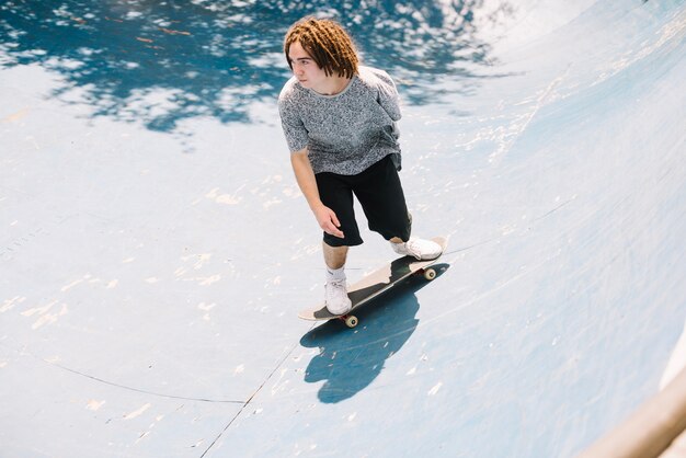 Skateboarder con dreadlocks praticare nel parco