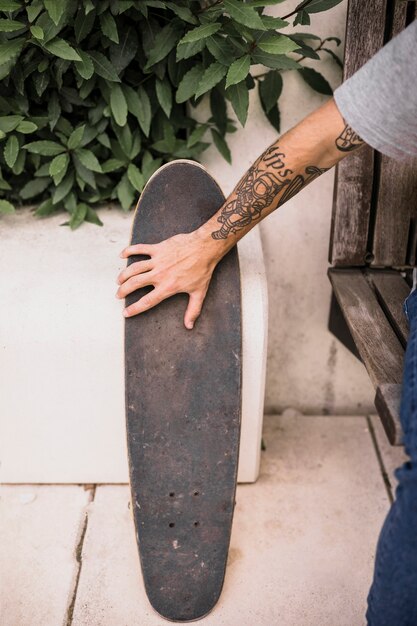 Skateboarder with tattoo in his hand holding skateboard