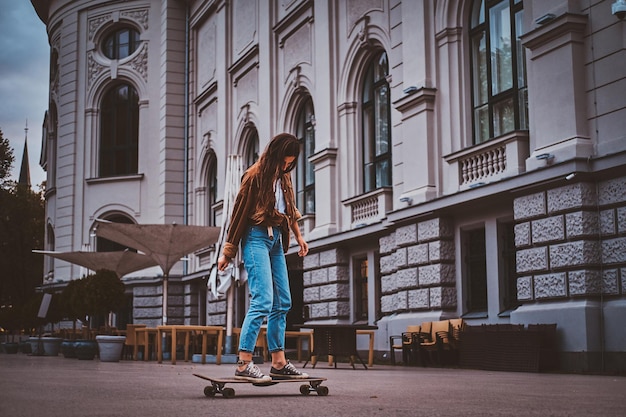 Free photo skater girl in denim is riding her longboard on the street.