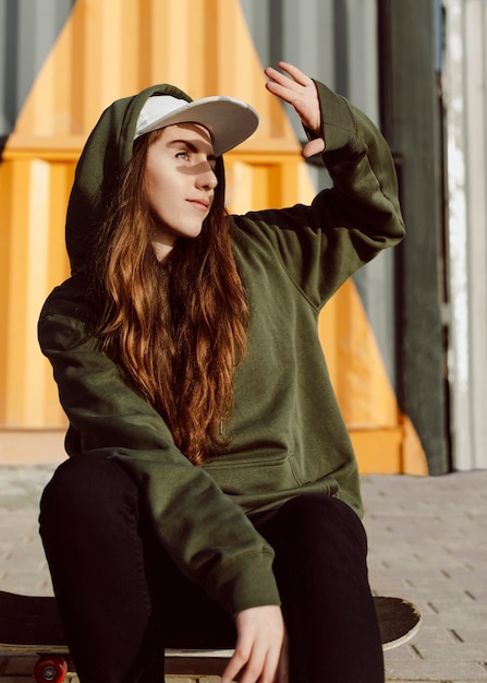 Free photo skater girl hiding her face from the sun with her head