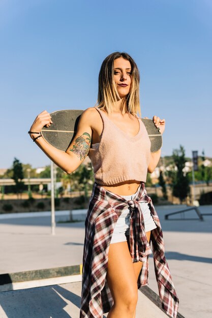 Skater girl holding board behind neck