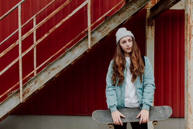 Free photo skater girl holding her skateboard in front of her