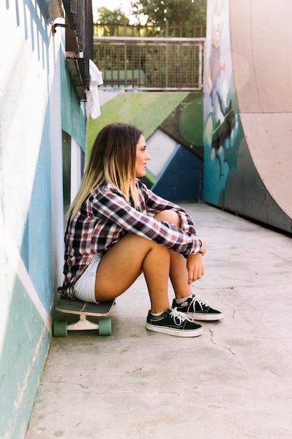 Free photo skater girl sitting on board