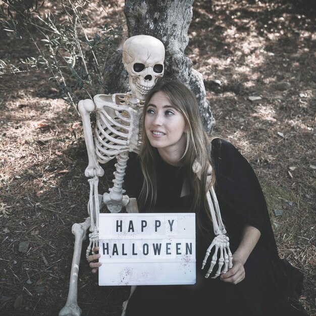 Skeleton hugging lady with tablet in dark clothes