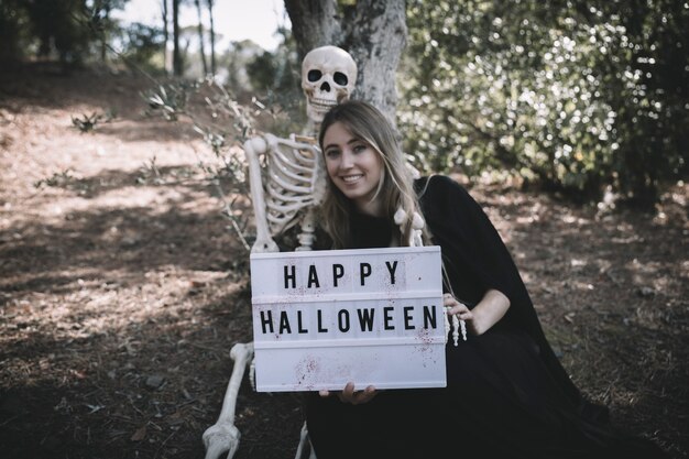 Skeleton sitting near smiling lady with tablet 