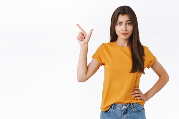 Skeptical arrogant and displeased young woman find new product suspicious and unworthy her attention smirk with disdain frowning judgemental pointing upper left corner Copy space