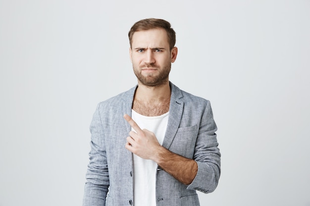 Free photo skeptical displeased bearded man pointing upper left corner