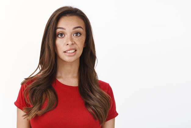 Skeptical displeased young picky feminine woman in red tshirt express disdain and scorn look disappointed slightly unsatisfied with result standing white background reluctant Copy space