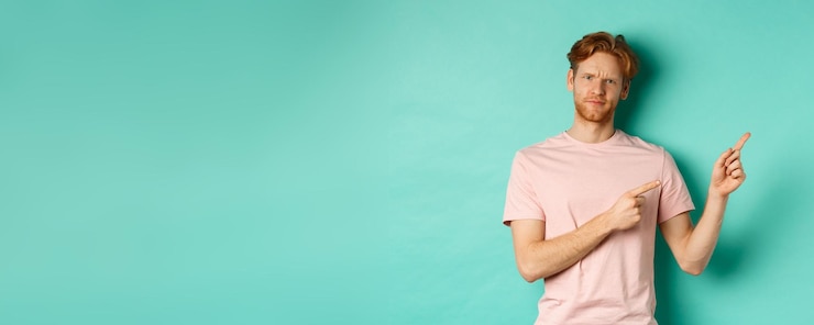 Free Photo skeptical and doubtful redhead man in tshirt pointing fingers at upper right corner showing promo of