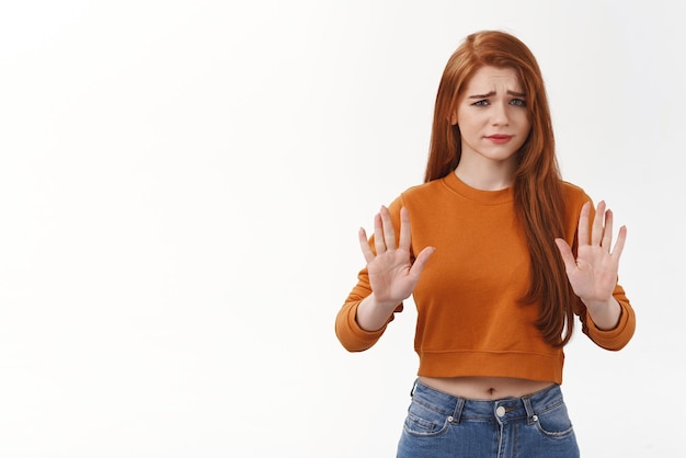 Skeptical and unimpressed pretty caucasian redhead woman rejecting terrible offer dont like and raise hands in stop gesture frowning with dismay and disappointment dislike strange suggestion