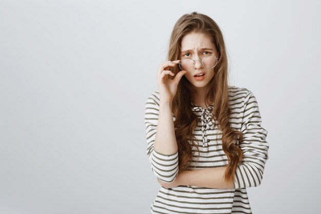 Skeptical woman in glasses looking with indifference