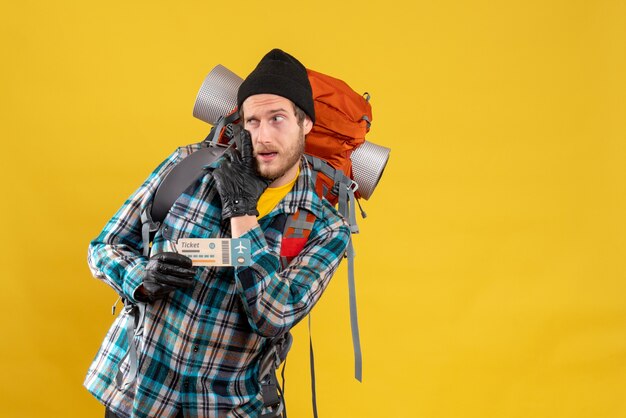 skeptical young backpacker with black hat holding airplane ticket