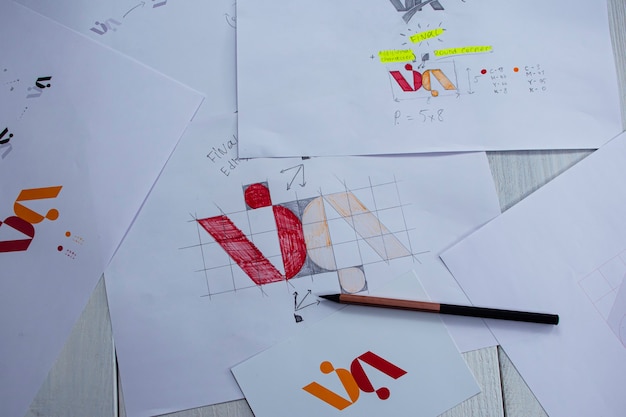Sketches and drawings of the logo printed on paper. development of logo design in the studio on a table.