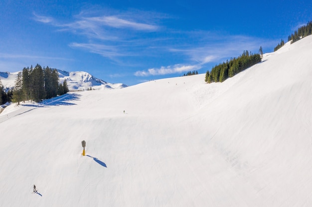 푸른 하늘 아래 눈 덮인 슬로프를 미끄러지는 스키어들이있는 스키장