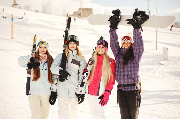 女の子の手にスキー用具。スキーウェアの明るい色。女の子は一緒に楽しい時間を過ごします。