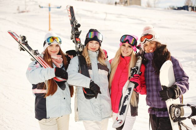 Ski equipment in hands of girls. Bright colors on ski clothes. Girls have a good time together.
