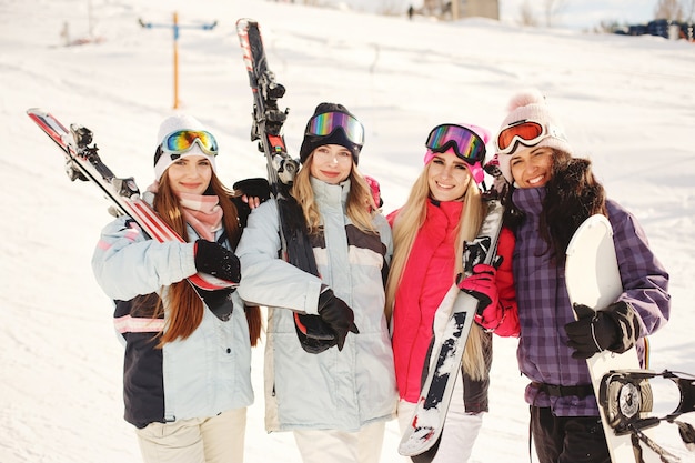 Ski equipment in hands of girls. Bright colors on ski clothes. Girls have a good time together.