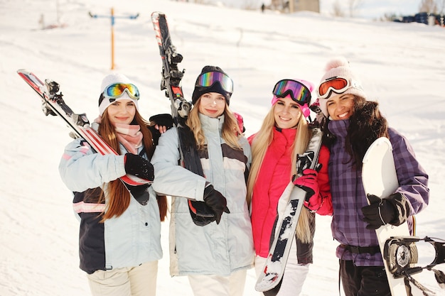 女の子の手にスキー用具。スキーウェアの明るい色。女の子は一緒に楽しい時間を過ごします。