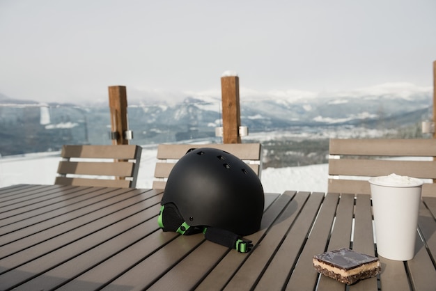 Ski helmet with sweet food and coffee on a table