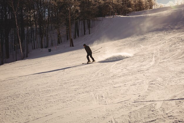 山の斜面でスキーをするスキーヤー
