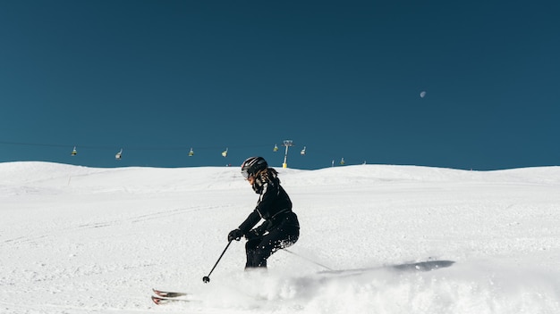 Skier skiing on a snowy surface wearing skiing outfit and helmet