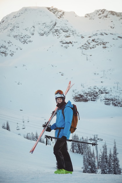 Лыжник стоит с лыжами на снежном пейзаже