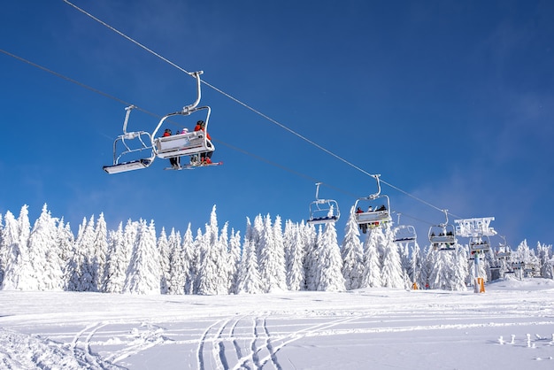 Skiers on a ski lift at a mountain resort with the sky and mountains 