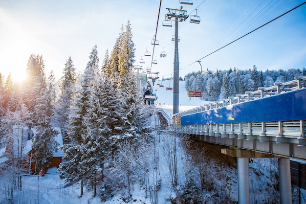 Skiers on the ski lift riding up at ski resort with beautiful forests