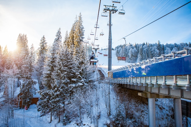 Лыжники на подъемнике едут на горнолыжном курорте с красивыми лесами