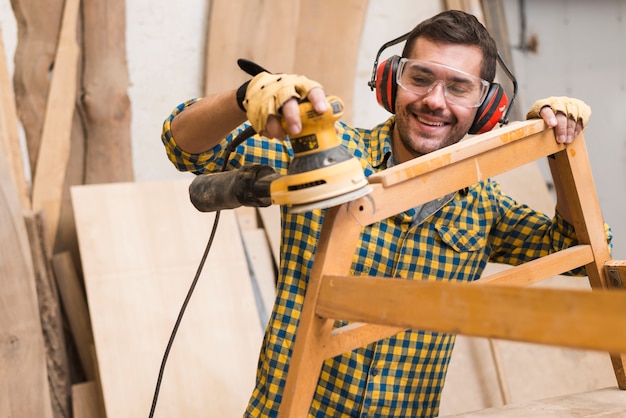 熟練した大工は、彼の家具を磨くための道具としてパワーサンダーを使用しています