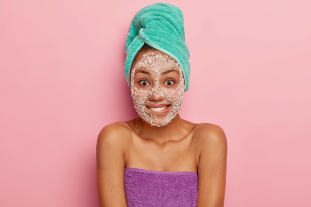 Skin care, beauty concept. Pretty lovely woman bites lower lip, looks happily, has hygiene treatments at home, cleans face from dirt and pores