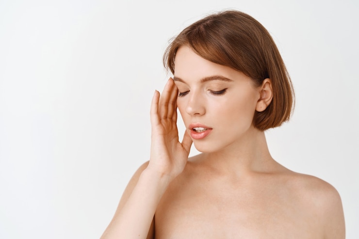 Free Photo skin care beauty. sensual young woman, naked shoulders, look aside and show natural beautiful face without make-up, nourish and apply skin care products for hydrated and detoxifying effect