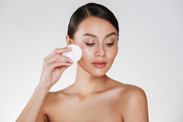 Уход за кожей и здоровое лечение женщины, снимающей макияж с лица с ватным тампоном, изолированным на белом