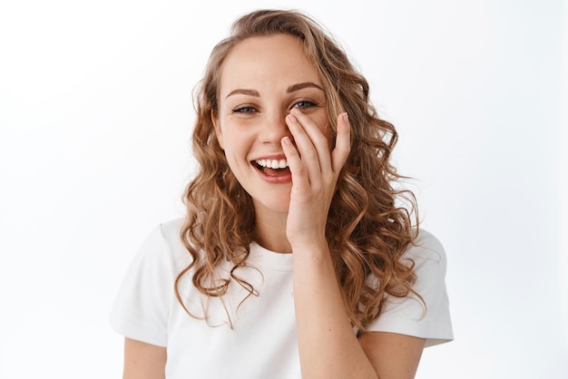 Skin care and women concept Beautiful smiling woman with natural facial skin without make up touching face and laughing standing over white background