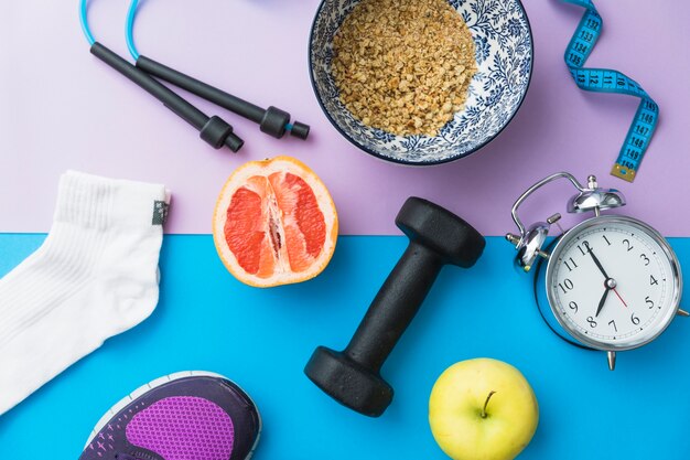 Skipping rope; measuring tape; sock; dumbbell; shoes; apple; halved orange fruit; alarm clock on dual backdrop