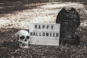 Free photo skull, gravestone and halloween tablet on ground