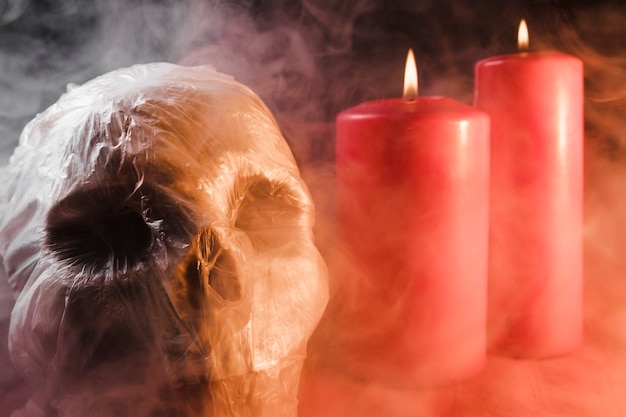 Skull in plastic bag and candles in smoke