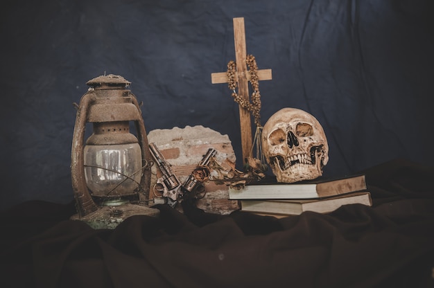 skulls in books with old lamps and guns crossed