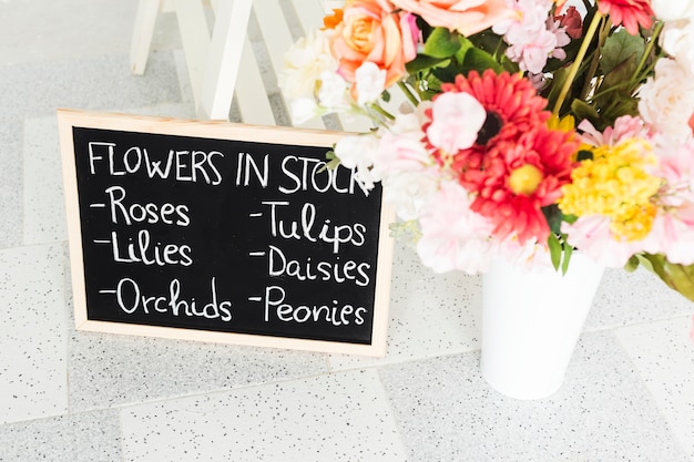 Free photo slate with flower names near vase on floor