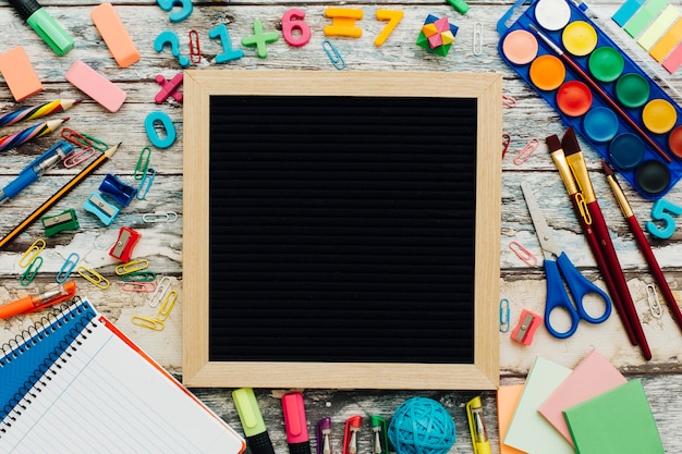 Foto gratuita ardesia con materiale scolastico su un tavolo di legno.