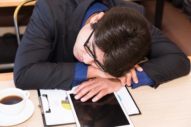 Free photo sleeping asian businessman in coffee shop