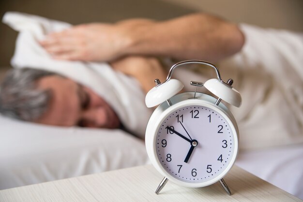 sleeping man disturbed by alarm clock early morning.  Sleepy you