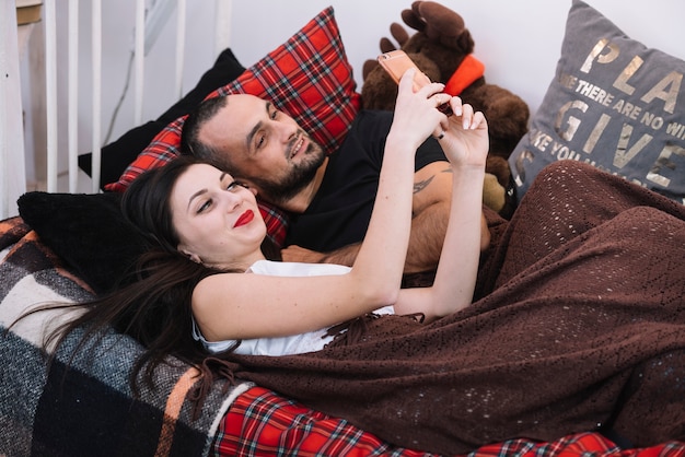 Sleeping man and woman with mobile phone on bed