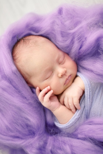 Sleeping newborn girl on a pink wool background closeup