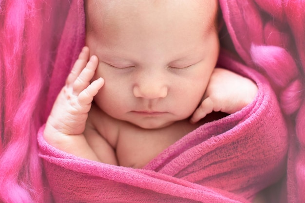 Спящая новорожденная девочка на розовом шерстяном фоне