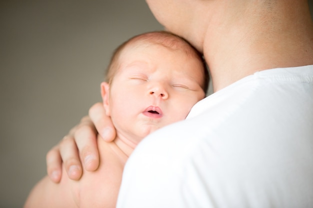 Sleeping newborn at the male shoulder