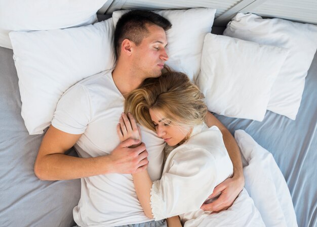 Sleeping young couple hugging on bed