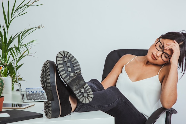 Free photo sleepy businesswoman with shoes on the table