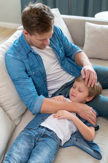 Sleepy son resting his head on father's legs