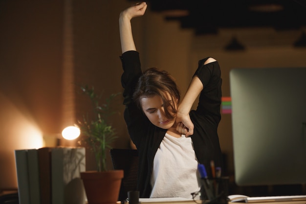 Free photo sleepy woman stretching in office
